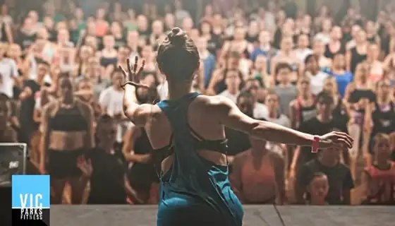 Woman dancing on stage in front of a large audience at a festival.